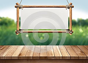 Wood table with hanging wooden sign on green nature blurred background