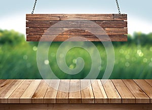 Wood table with hanging wooden sign on green nature blurred background