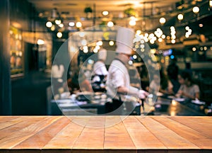 Wood table top with blur chef cooking in bar restaurant