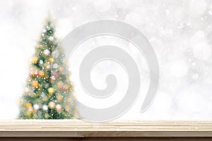 Wood table top on blur Christmas tree background in snowfall
