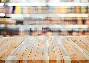 Wood table top on blur of drinking product shelf background in  supermarket or grocery background