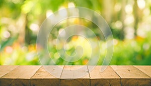 Wood table top on blur of fresh green abstract from garden