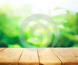 Wood table top and blur of fresh green bokeh from garden