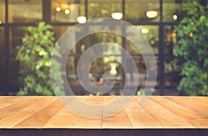 Wood table top on blur glass wall cafe background.