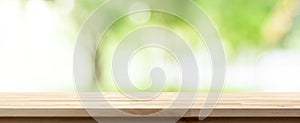 Wood table top on blur green background of trees in the park