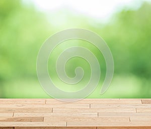 Wood table top on blur green background of trees in the park.