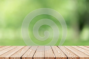 Wood table top on blur green background of trees in the park.