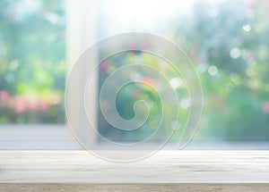 Wood table top on blur of window with garden flower background