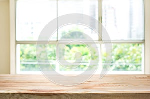 Wood table top on blur of window glass and abstract green garden