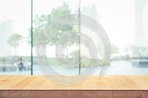 Wood table top on blur window glass,wall background with city view.For montage product display or design key visual