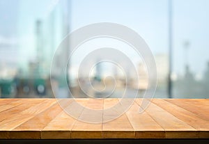 Wood table top on blur window glass,wall background with city view.For montage product display or design key visual