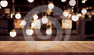 Wood table top on blurred of counter cafe shop with light bulb background