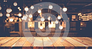 Wood table top on blurred of counter cafe shop with light bulb background