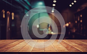 Wood table top on blurred of counter cafe shop with light bulb