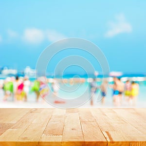 Wood table top with blurred people at the beach as background