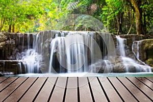 Wood table top on blurred waterfall deep forest
