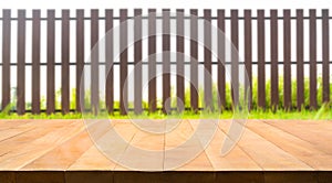 Wood table top with fence and grass in garden background.