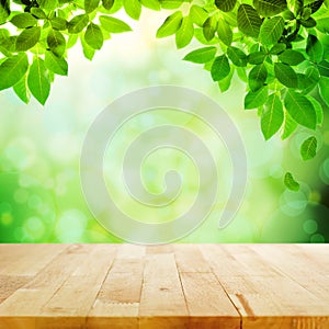 Wood table top with green leaf & blur bokeh background