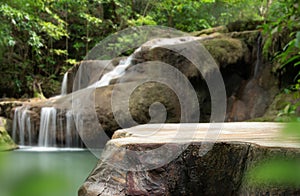 Wood table top podium floor in outdoor waterfall green tropical forest nature background.Natural water product present placement