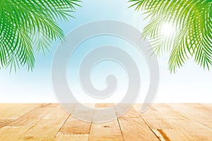 Wood table top on summer tropical sky background with green coconut leaves