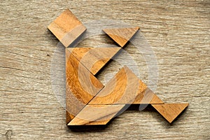 Wood tangram puzzle as man sit with read book