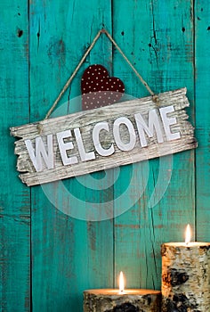 Wood welcome sign with red heart by candlelight hanging on antique teal blue background