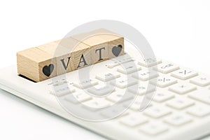 Wood word VAT and Wood Heart placed on a white calculator as background finance concept and business concept