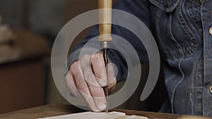 A wood worker cuts out a dovetail on a pine board with a chisel. dovetail joinery is done with a hand tool. woodworker makes an