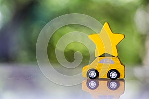 Wood yellow toy car carry a yllow star on roof against nature background