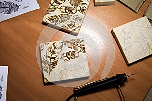 Woodburning. Burning on wood - a pattern with feathers on the li