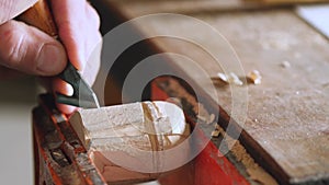 A woodcarver carves a helmet of a robot or a knight with a knife. wood carving in a carpentry workshop. the art of woodcarving and