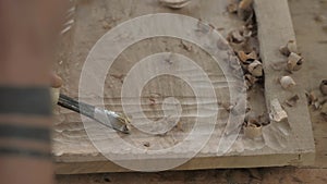A woodcarver processes a walnut wood board with a chisel. handmade tea tray