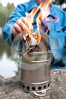 Woodchip stove close up with fire and hands on background