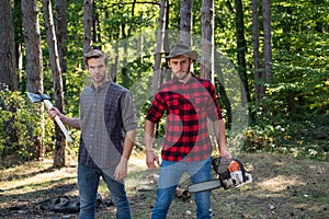 Woodcutters with chainsaw lumberjacks with axe. Hipsters men on serious face with axe. Lumberjack brutal and bearded