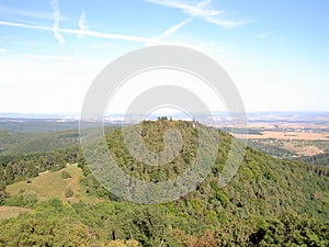 Wooded hill with a turret from above, in the background are forests, meadows, fields, villages and towns