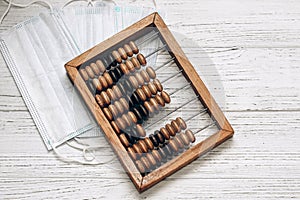 wooden abacus with medical masks on a white background. Treatment cost concept.