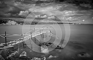 Wooden abandoned pier at sunset. Longexposure, with stormy cloudy sky.