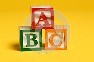 Wooden ABC blocks on yellow background