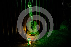 An wooden acoustic guitar is against a grunge textured wall. The room is dark with a spotlight for your copyspace