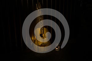 An wooden acoustic guitar is against a grunge textured wall. The room is dark with a spotlight for your copyspace