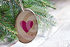 Wooden adornment with heart and xmas inscription hanging on christmas tree photo
