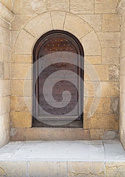 Wooden aged vaulted ornate door and stone wall