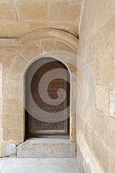 Wooden aged vaulted ornate door and stone wall