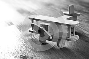 Wooden airplane toy over textured wooden background. retro style image. black and white old style photo