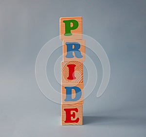 Wooden alphabet ABC toy blocks with the text: pride. Isolated kids alphabet cubes on blue background with copy space
