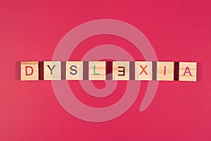 Wooden alphabet blocks with DYSLEXIA word on pink background