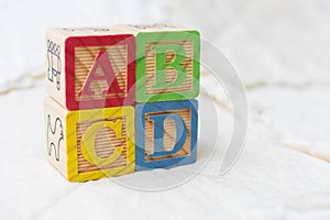 Wooden Alphabet Blocks on Quilt Spelling ABCD Stacked on Angle
