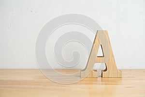 Wooden A alphabet letter on wooden table with white concrete wall background copy space. Top class, score, quality ranking