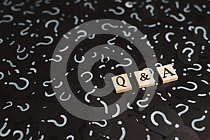 Wooden alphabet tiles with Q&A letter on black paper with QUESTION MARK