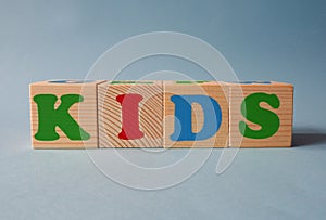 Wooden alphabet toy blocks with the text: Kids.  kids ABC cubes on blue background